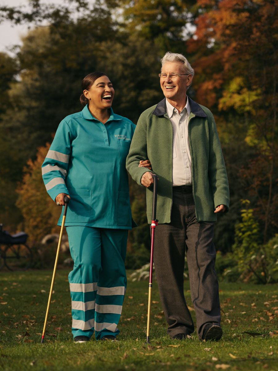 Support worker and client walking in a garden